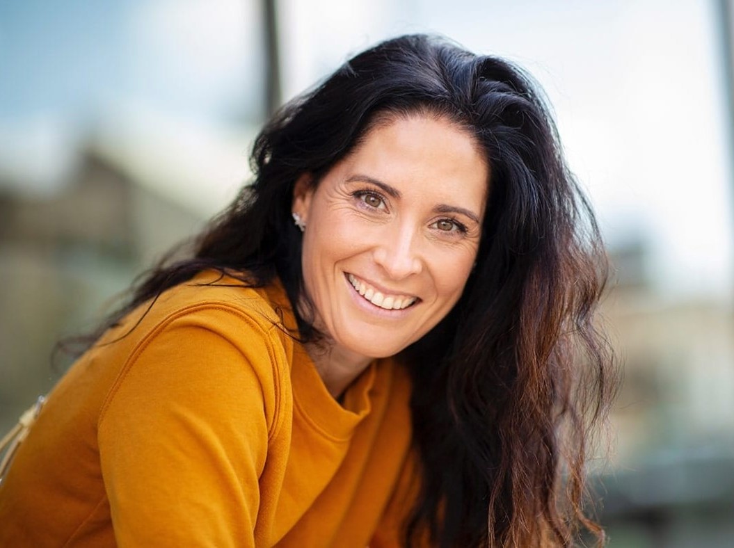 woman in yellow shirt with long, dark hair smiling with teeth